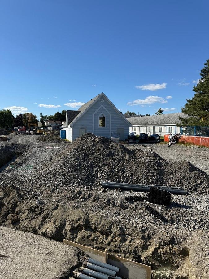 Tranchée de fondation et conduits devant un bâtiment existant à Ottawa